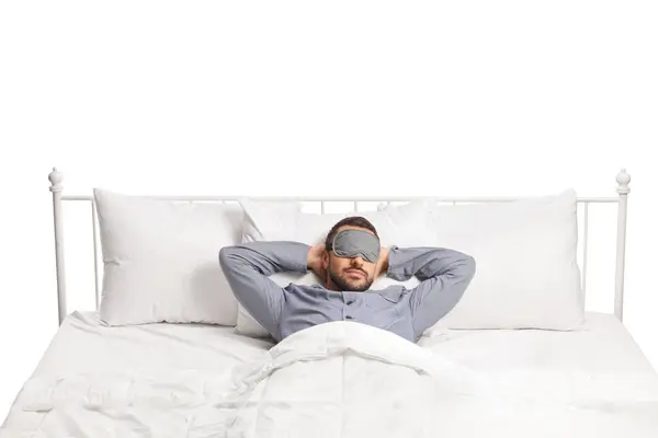 年轻男子躺在床上 戴着睡面罩 与白色背景隔离 — 图库照片