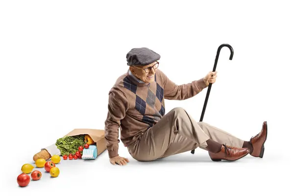 白い背景に隔離された食料品袋で床に落ちる杖を持つ高齢男性 — ストック写真