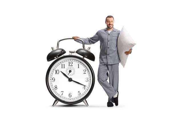 Smiling Man Pajamas Leaning Big Alarm Clock Holding Pillow Isolated — Stock Photo, Image