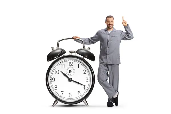 Young Man Pajamas Leaning Big Alarm Clock Pointing Isolated White — Stock Photo, Image