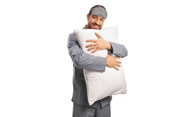 白い背景に隔離された枕と微笑みを抱く睡眠マスクとパジャマの幸せな男 — ストック写真
