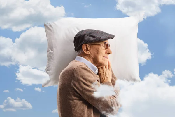 Profile shot of an elderly man sleeping on a pillow up in the clouds