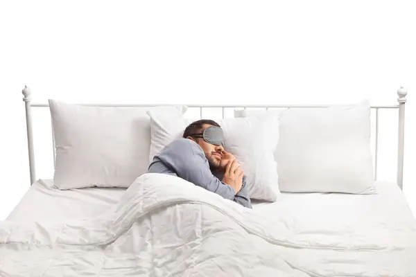 Man wearing a mask and sleeping alone in a double bed isolated on white background