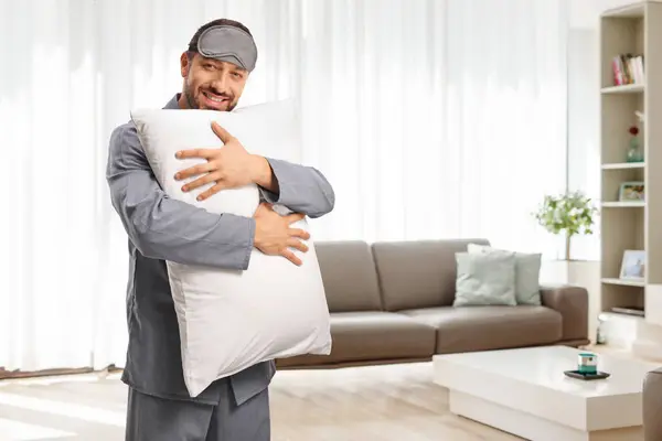 穿着睡衣 戴着睡眠面具 抱着枕头在客厅里的快乐男人 — 图库照片
