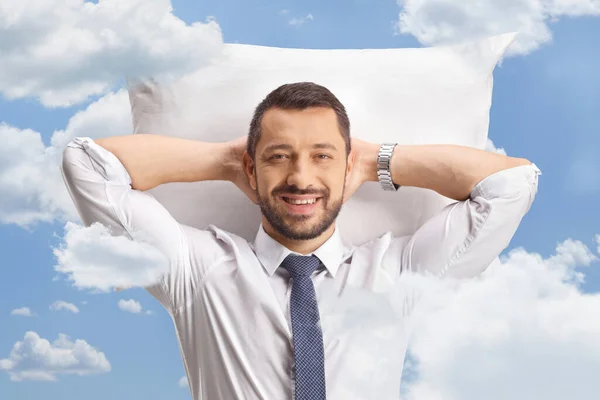 Portrait of a businessman resting on a pillow in a shirt and tie in the sky