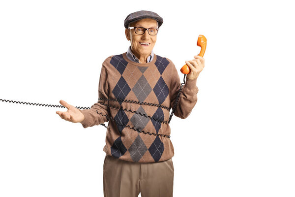 Пожилой человек запутался в кабеле от винтажного ротационного телефона, изолированного на белом фоне