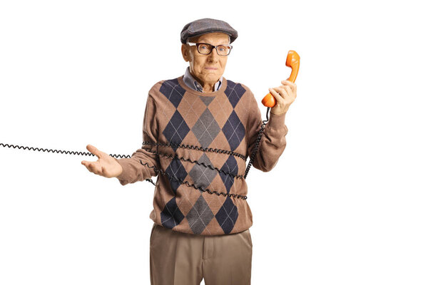 Испуганный пожилой человек запутался в кабеле от винтажного ротационного телефона, изолированного на белом фоне