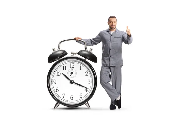 Man Pajamas Leaning Big Alarm Clock Gesturing Thumbs Isolated White — Stock Photo, Image