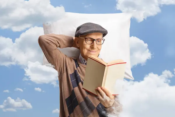 Oudere Man Rust Een Kussen Leest Een Boek Tussen Wolken — Stockfoto