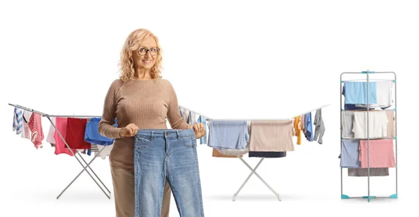 Mature Woman Holding Pair Jeans Front Clothes Drying Racks Isolated — Stock Photo, Image