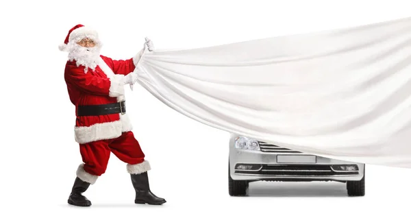 白い背景に隔離された銀製の車の前に白い布を引っ張るサンタクロース — ストック写真