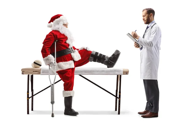 Lekarz Piszący Stojący Przed Świętym Mikołajem Ranną Nogą Białym Tle — Zdjęcie stockowe