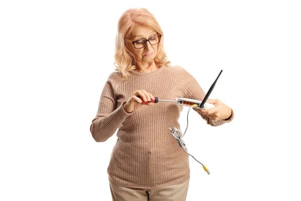 Mulher Madura Confusa Consertando Roteador Com Uma Chave Fenda Isolada — Fotografia de Stock