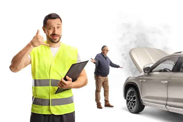 Road assistant gesturing a phone call in front of a man with a car problem isolated on white background