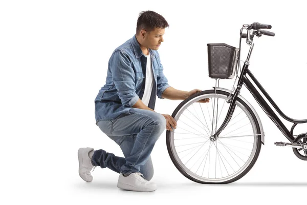 Молодой Человек Стоит Коленях Смотрит Велосипед Спустило Колесо Изолированы Белом — стоковое фото