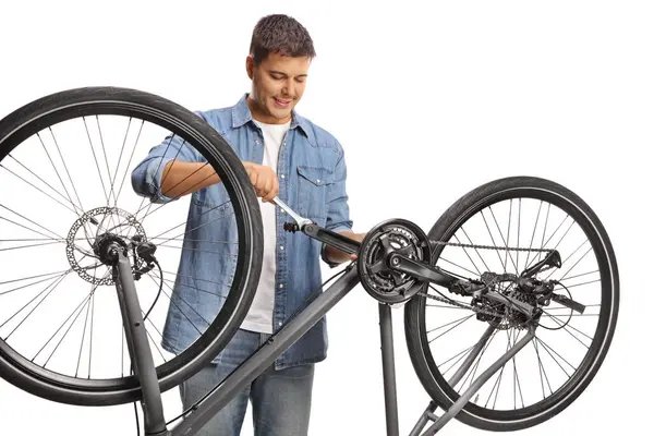 年轻人用隔离在白色背景上的扳手固定自行车踏板 — 图库照片