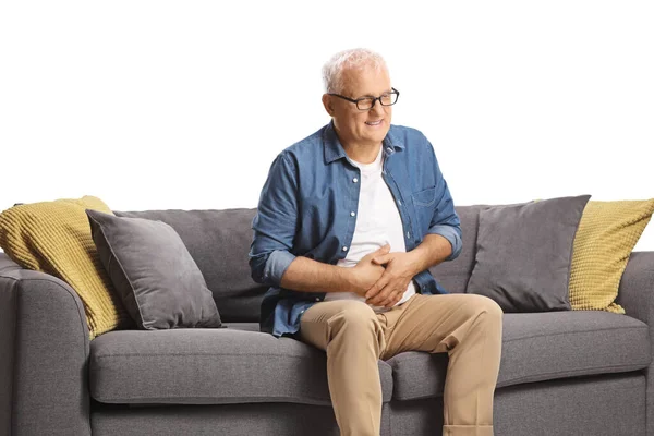 白い背景に隔離されたソファの上に座っている腹部の痛みを持つ成熟した男 ヘルスケアの概念 — ストック写真