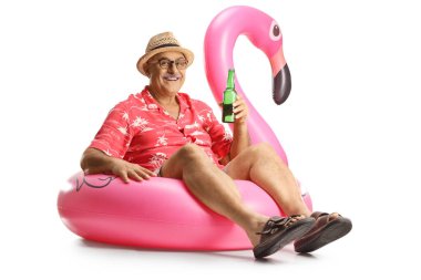 Olgun bir adam, şişme flamingo bir halkanın üzerinde oturuyor ve elinde beyaz arka planda izole edilmiş bir şişe bira tutuyor.