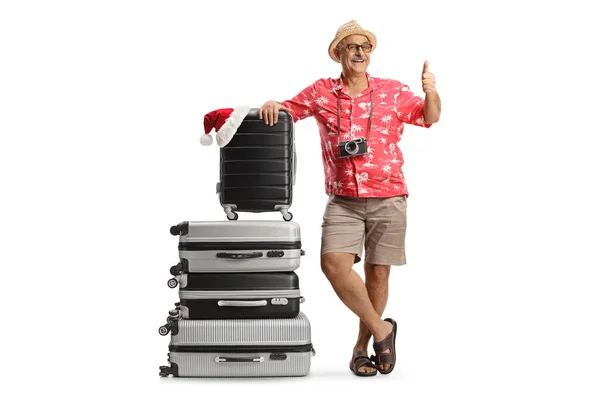 陽気な成熟した男は スーツケースの山に傾き 親指を示す クリスマスの旅行の概念 — ストック写真