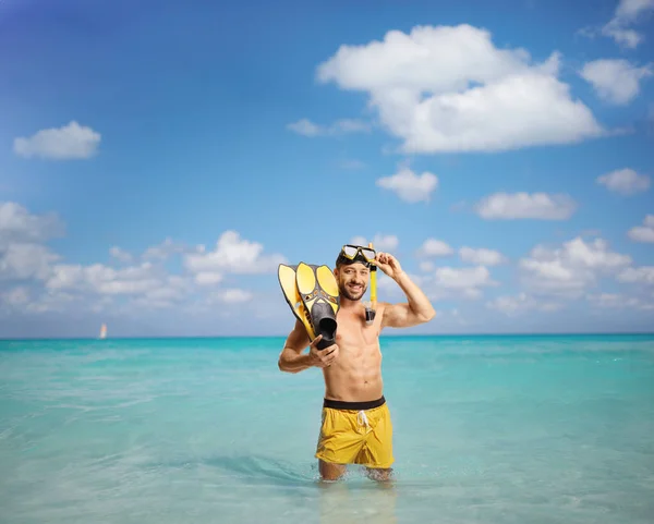 青いカリブ海に立っているシュノーケリングフィンとマスクを持つ男 — ストック写真
