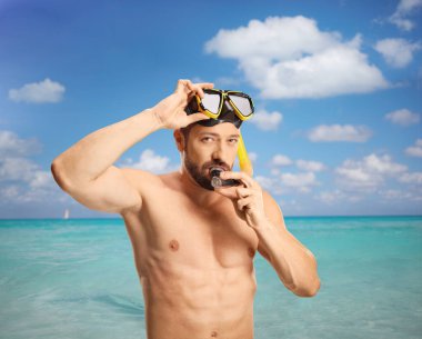 Denizde duran ve dalış maskesi takan bir adam.