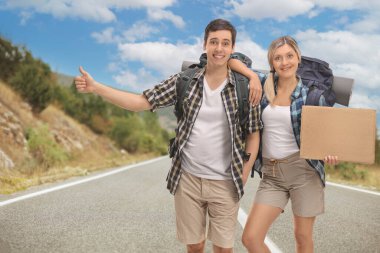 Birkaç yürüyüşçü otostop yapıyor ve ellerinde boş bir karton tabela var.