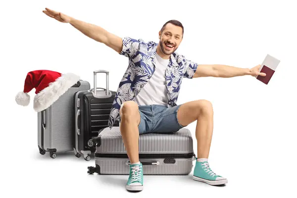 クリスマス旅行でハッピーな男性観光客 スーツケースに座って 白い背景で孤立した飛行するために腕を広げる — ストック写真