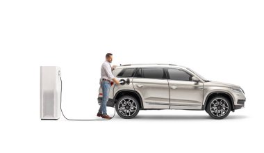 Beyaz arka planda izole edilmiş şarj noktasında SUV 'si olan elektrikli araba sahibi.