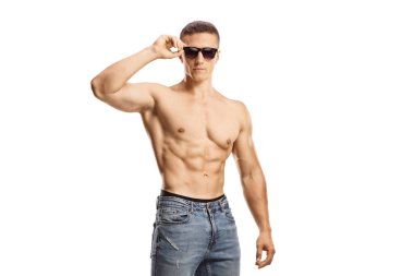 Beyaz arka planda izole edilmiş kot pantolon ve güneş gözlüğü takan üstsüz genç adam.