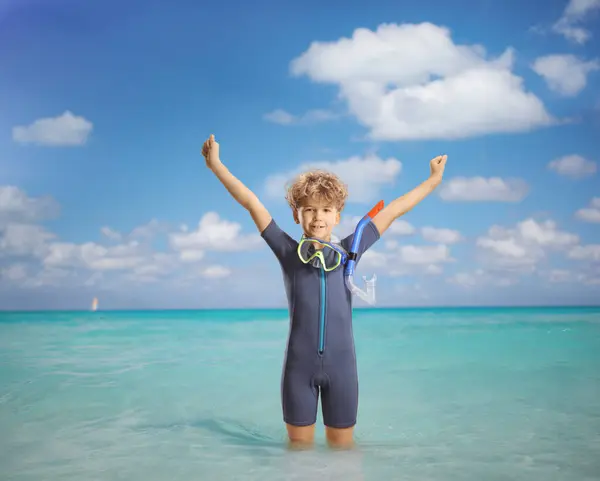 穿着潜水衣的男孩站在海里举起胳膊 — 图库照片