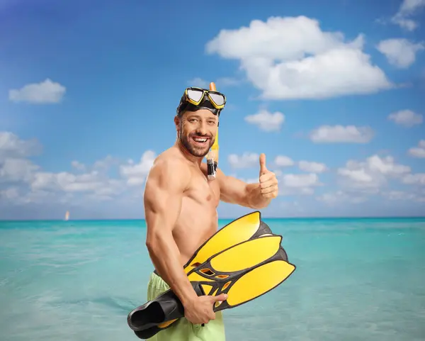 身穿泳衣 戴着潜水面罩 带着潜水鳍的快乐的年轻人在海面上摆弄着大拇指 — 图库照片