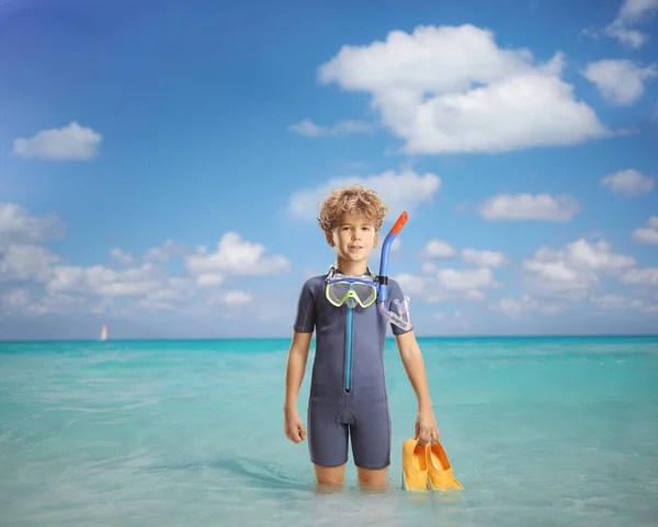 穿着湿西服的男孩拿着游泳的鳍站在海里 — 图库照片