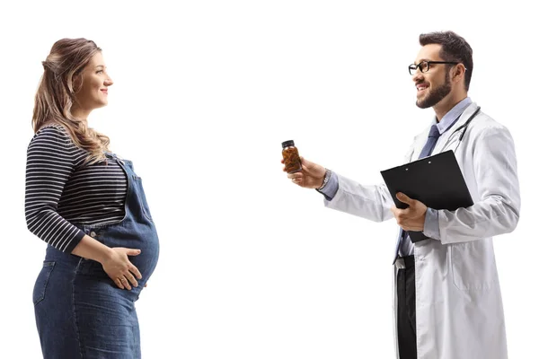 白い背景に隔離された妊婦にビタミン錠のボトルを与える医師のプロフィールショット — ストック写真