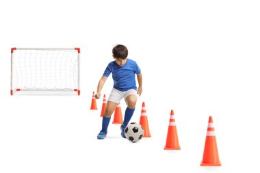 Çocuk engelli konilerle futbol antrenmanı yapıyor ve beyaz arka planda izole edilmiş mini bir gol.