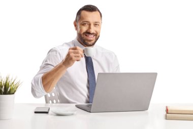 Espresso içen ve beyaz arka planda izole edilmiş bir dizüstü bilgisayar üzerinde çalışan bir adam.