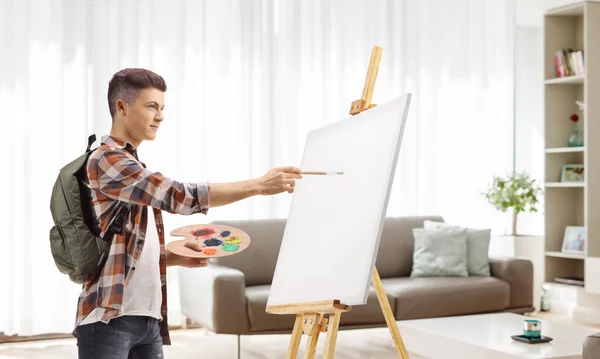 Male student painting on a canvas in an apartment