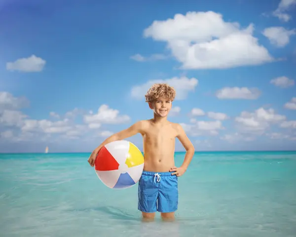 男孩站在海里 拿着一个海滩球 — 图库照片