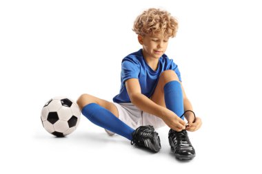 Futbol takımındaki çocuk beyaz arka planda izole edilmiş kramponları giyiyor.