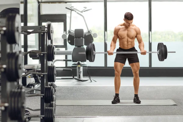 一个强壮的肌肉男子在体育馆举重的全长肖像 — 图库照片