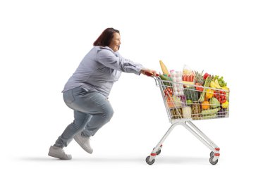 Beyaz arka planda izole edilmiş bir alışveriş arabasıyla koşan büyük beden bir kadının tam boy profil çekimi.