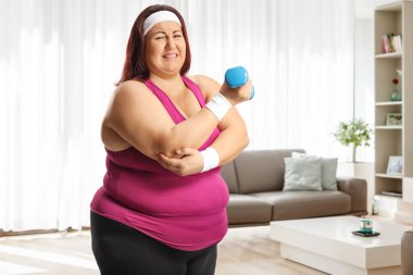 Dambılı tutan şişman bir kadın ve acılı dirseğini bir dairede tutuyor.