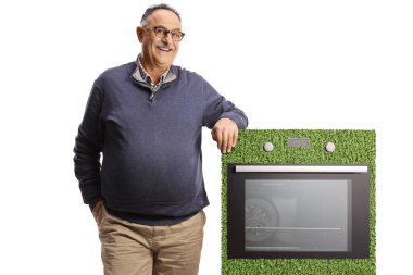 Beyaz arka planda izole edilmiş enerji verimli bir ocağa yaslanan gülümseyen olgun bir adam.