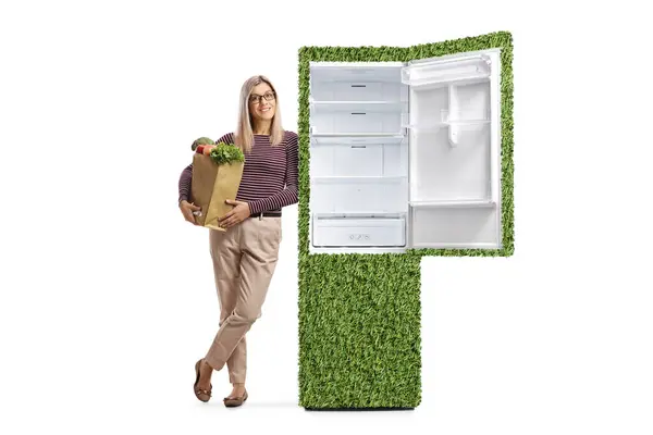提着购物袋的女人靠在一个绿色环保冰箱上 与白色背景隔离 — 图库照片