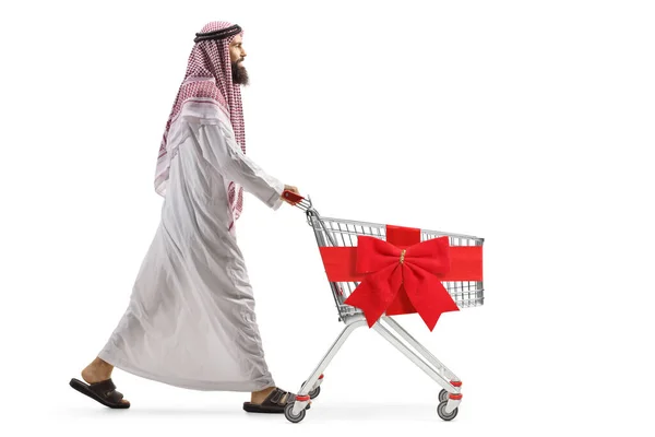 沙乌地阿拉伯人推着一辆空购物车 红色缎带弓与白色背景隔离的全景照片 — 图库照片