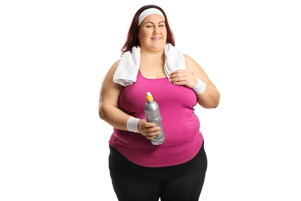 穿着运动服的胖女人 脖子上缠着毛巾 手里拿着一个白色背景的瓶子 — 图库照片