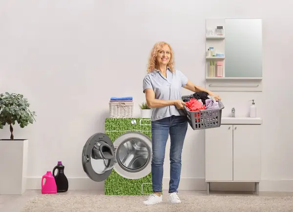 電源効力洗濯機付きのバスルームに洗濯用のバスケットを持っている女性 — ストック写真