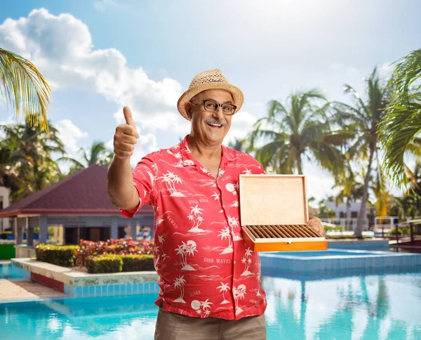 一个成熟的游客在游泳池边挖了一盒雪茄 给大拇指做手势 — 图库照片