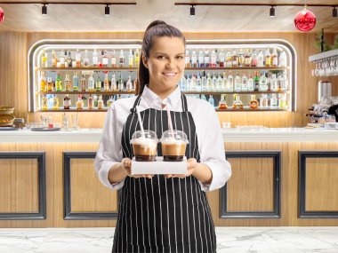 Genç bayan garson barın önünde bir fincan kahve tutuyor.