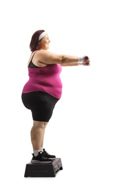 Basamakta duran ve beyaz arka planda izole edilmiş egzersiz yapan şişman bir kadının tam boy profil çekimi.