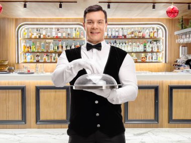 Garson bir barda şeffaf kapaklı bir tepsi tutuyor.